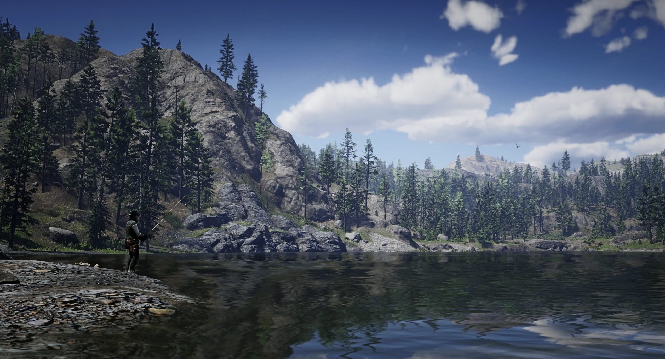 A fisherman stands beside a mountain lake and pine-covered cliffs in Red Dead Redemption 2 with Simple Realism enabled.