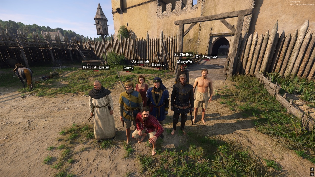 Players gather beside a wooden palisade and castle gate in Kingdoms Connected.
