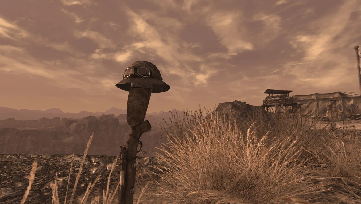 An NCR helmet rests on the stock of an upright rifle as a battlefield memorial near Camp Forlorn Hope.