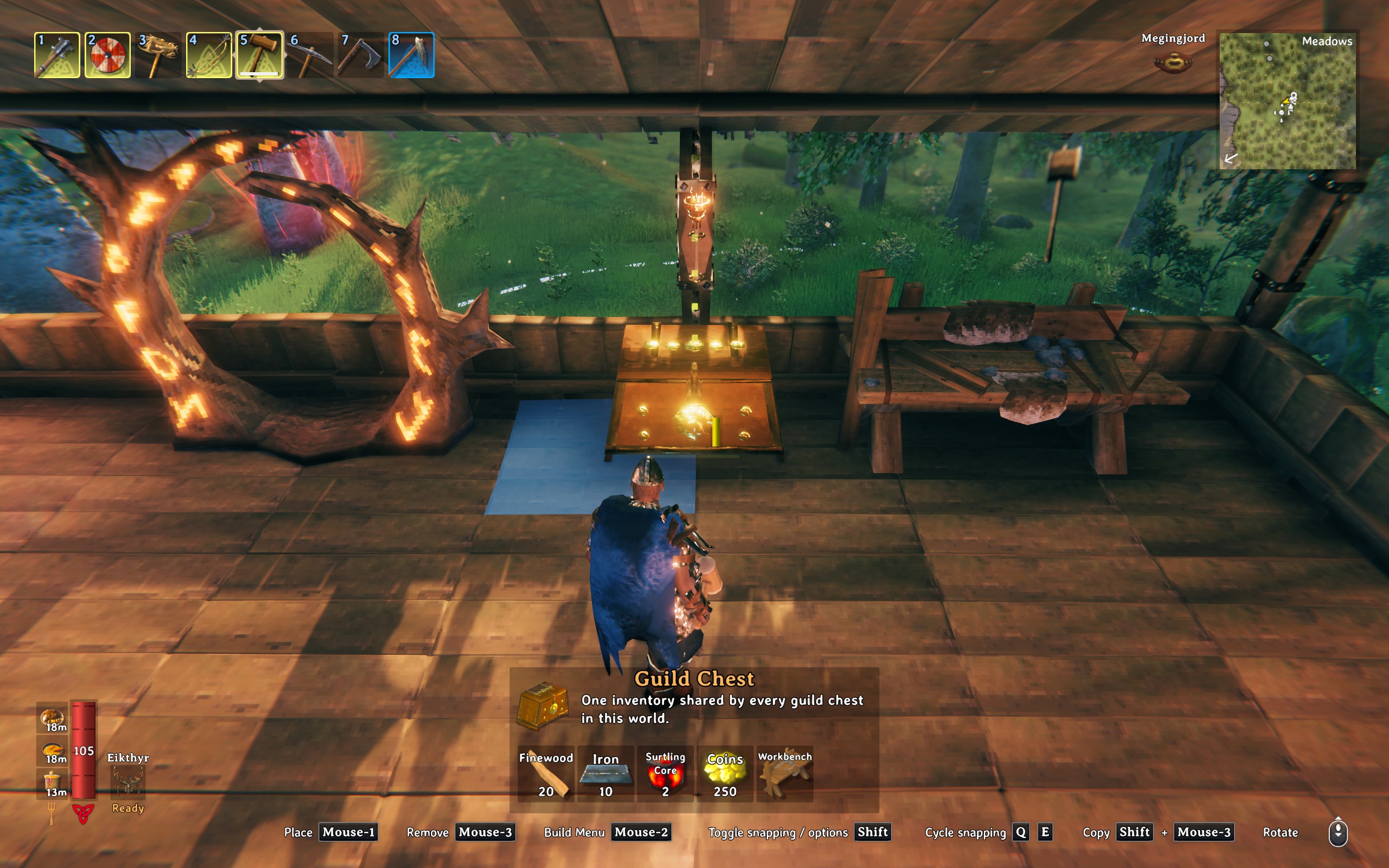 A Valheim character places a gold Guild Chest inside a wooden building beside a portal.