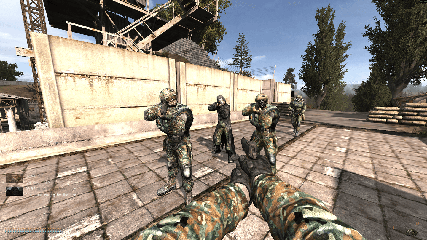 Four armed stalkers face the player beside an industrial compound wall in Anomaly, with dialogue subtitles in the lower left.