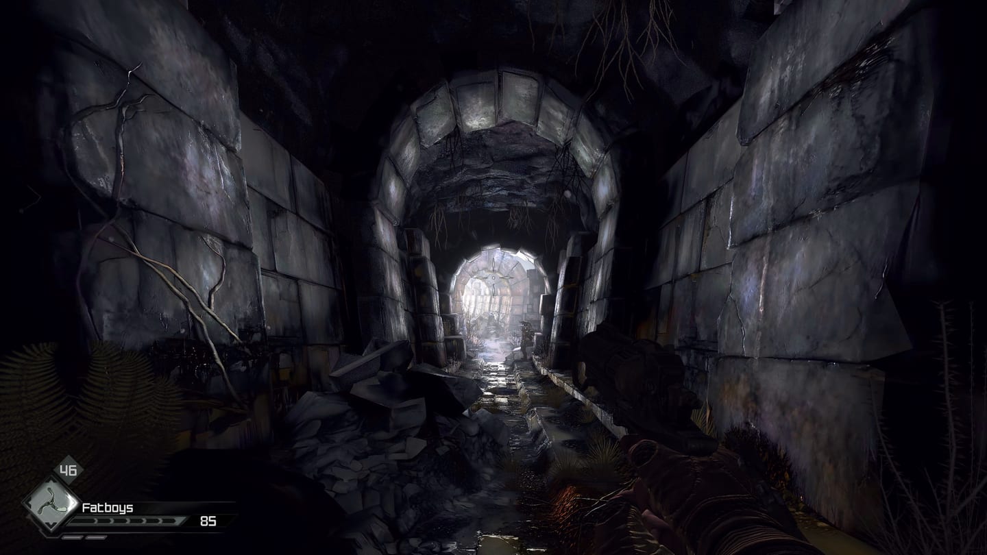 A weapon points down a ruined stone tunnel toward a bright opening, with roots and rubble nearby.